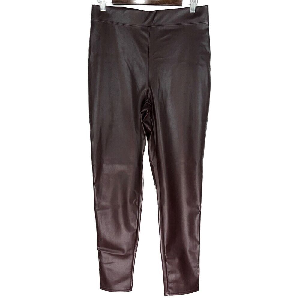 Dark brown faux leather leggings hanging on a hanger against a plain white background.