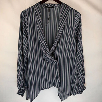 A long-sleeve wrap-style blouse with vertical navy, gray, and white stripes, hanging on a dark wooden hanger against a plain off-white fabric backdrop.