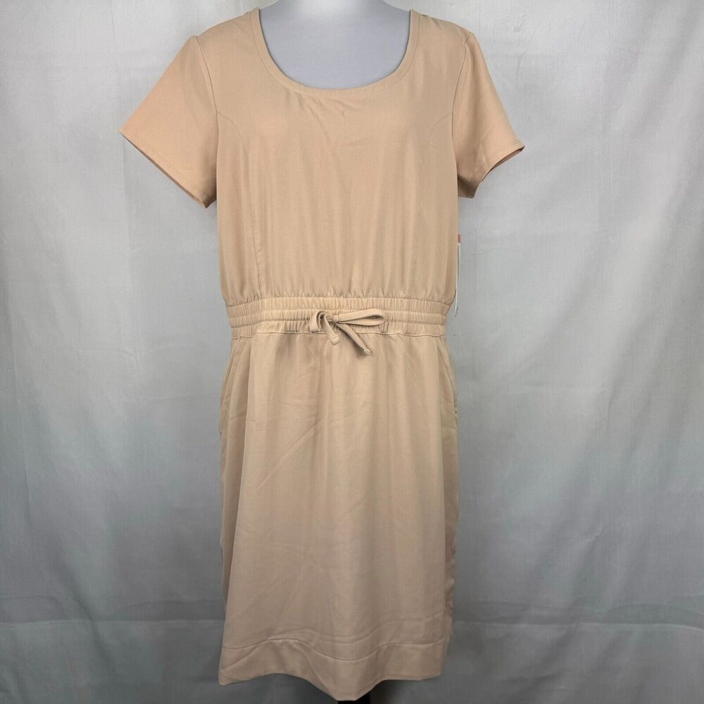 A beige short-sleeve babydoll dress with a scoop neckline and a drawstring waist, displayed on a mannequin against a light gray fabric backdrop.