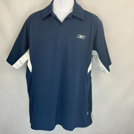 A navy blue short-sleeve athletic polo shirt with white side panels and a white Reebok logo on the chest, displayed on a white mannequin torso against a light gray fabric backdrop.