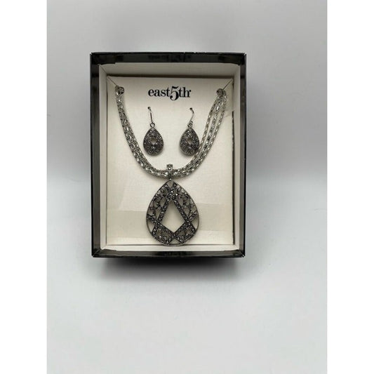 A silver-toned jewelry set featuring a teardrop pendant necklace and matching drop earrings, presented inside a black box with a cream insert. The brand name 'east5dr' is printed on the insert.