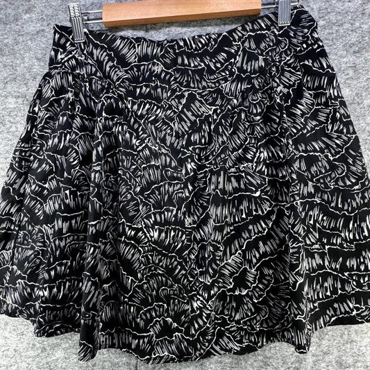 Black and white textured ruffled mini skirt with a flared silhouette, hanging on a wooden hanger against a gray felt background.