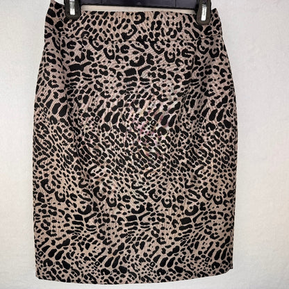 A leopard print pencil skirt in beige and black, hanging on a black hanger against a light gray textured wall.