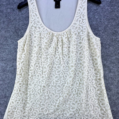 An off-white lace sleeveless top with a gathered neckline, hanging on a black hanger against a textured gray background.