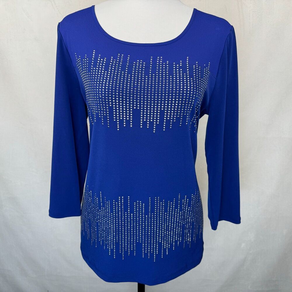 A royal blue long-sleeve scoop-neck top with silver rhinestone vertical line patterns on the chest and lower skirt, displayed on a white mannequin torso against a white fabric backdrop.