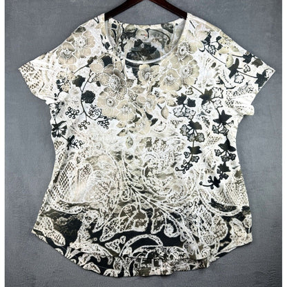 A short-sleeve V-neck top with an all-over abstract floral and lace-like print in black, beige, and off-white, hanging on a dark wooden hanger against a textured gray background.