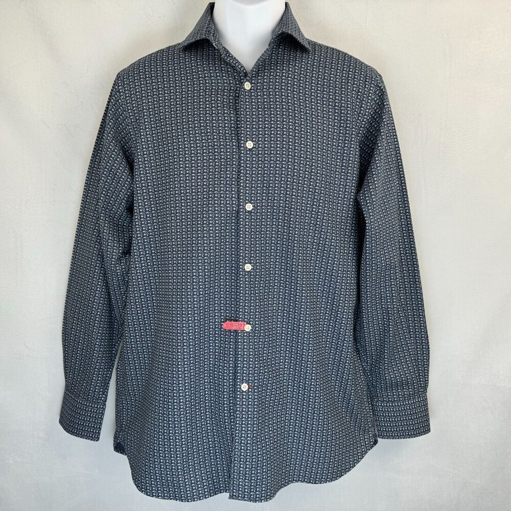 A long-sleeve button-up shirt with a small repeating geometric pattern in navy and white, displayed on a white mannequin torso against a light gray fabric backdrop.