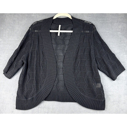 A black open-front knit cardigan sweater with three-quarter sleeves and a textured chevron pattern, laid flat on a light gray textured background.