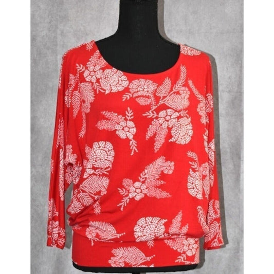A red long-sleeve top with a white floral and leafy pattern, displayed on a black mannequin torso against a gray textured background.