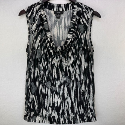 A sleeveless V-neck top with a black, gray, and white abstract pattern, hanging on a dark hanger against a light textured wall.