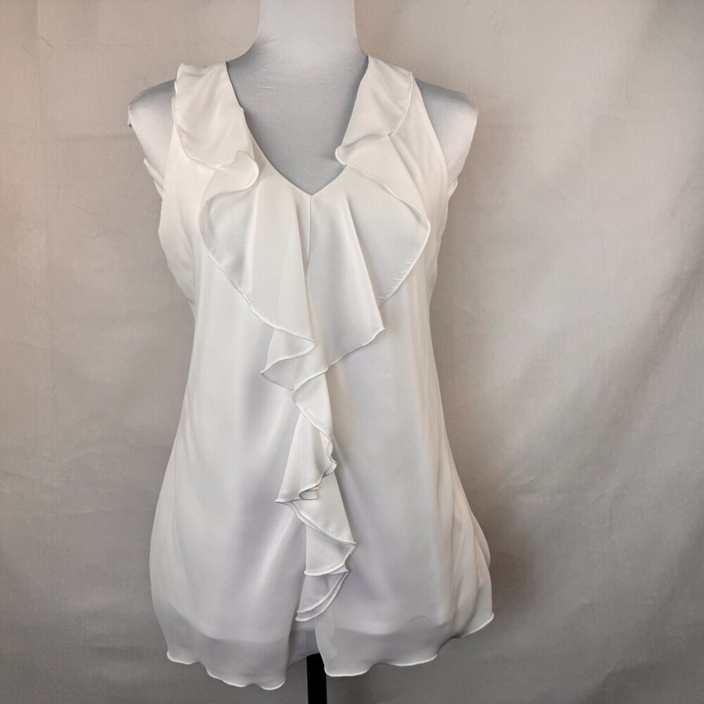 A white sleeveless blouse with layered ruffle details, displayed on a gray mannequin torso against a light gray fabric backdrop.