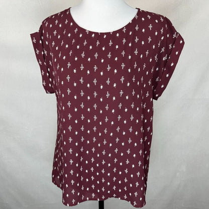 A women's short-sleeve top in burgundy with a white allover floral pattern, displayed on a white mannequin torso against a light gray fabric backdrop.