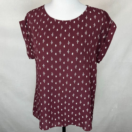 A women's short-sleeve top in burgundy with a white allover floral pattern, displayed on a white mannequin torso against a light gray fabric backdrop.
