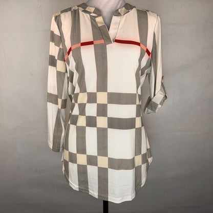A long-sleeve plaid tunic top with a white, gray, and beige checkered pattern and a thin red stripe across the chest, displayed on a mannequin against a gray background.