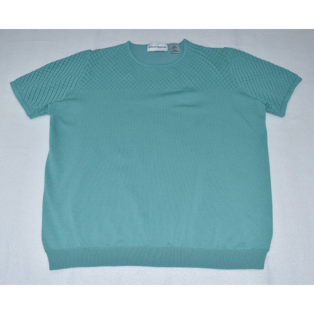A short-sleeve knit sweater in a muted teal color, laid flat on a light gray background. The knit pattern is textured on the upper chest and shoulders, with a smoother ribbed hem and cuffs.