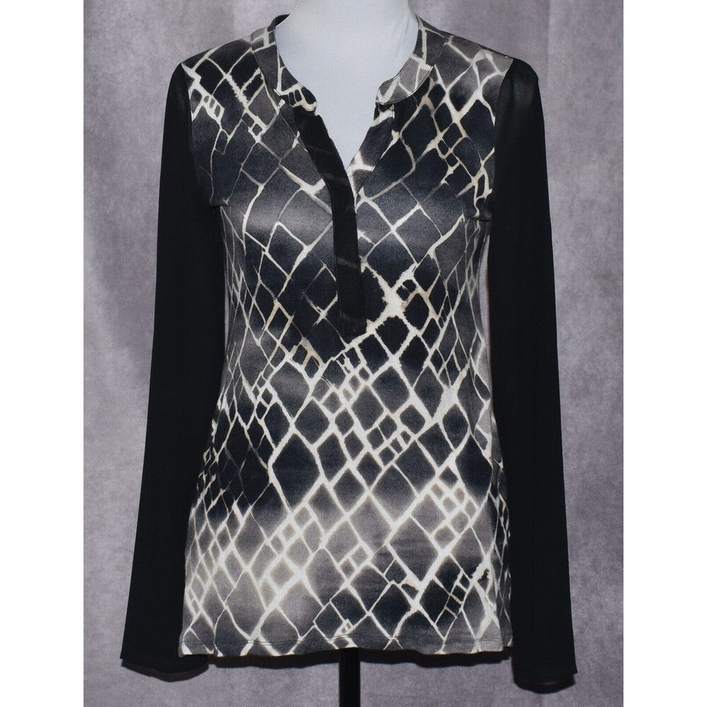 A women's long-sleeve blouse displayed on a mannequin torso against a textured gray backdrop. The top features a black and white snakeskin pattern on the body with solid black sleeves and a black tie detail at the collar.