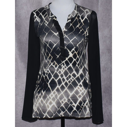 A women's long-sleeve blouse displayed on a mannequin torso against a textured gray backdrop. The top features a black and white snakeskin pattern on the body with solid black sleeves and a black tie detail at the collar.