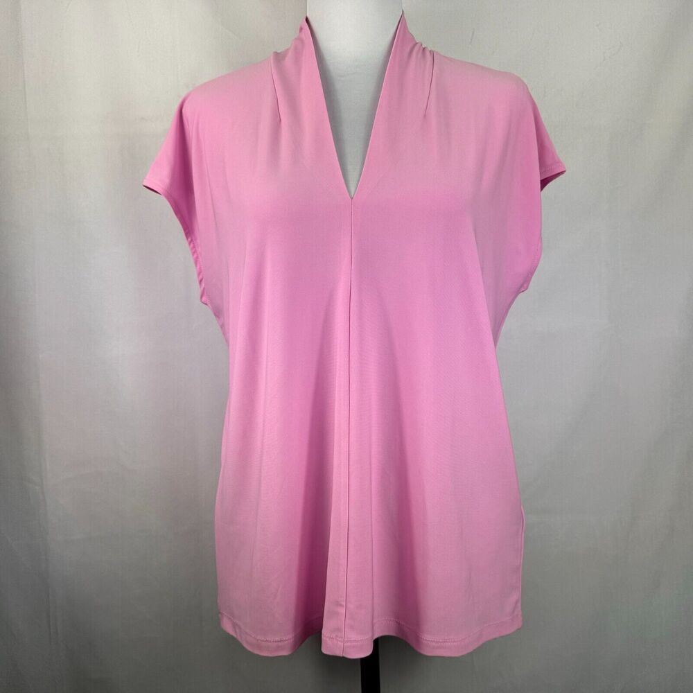 A pink short-sleeve top with a split V-neckline, displayed on a mannequin torso against a light gray fabric backdrop.