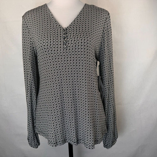 A long-sleeve V-neck blouse with a small-scale black and white geometric pattern, displayed on a mannequin torso against a light gray fabric backdrop.
