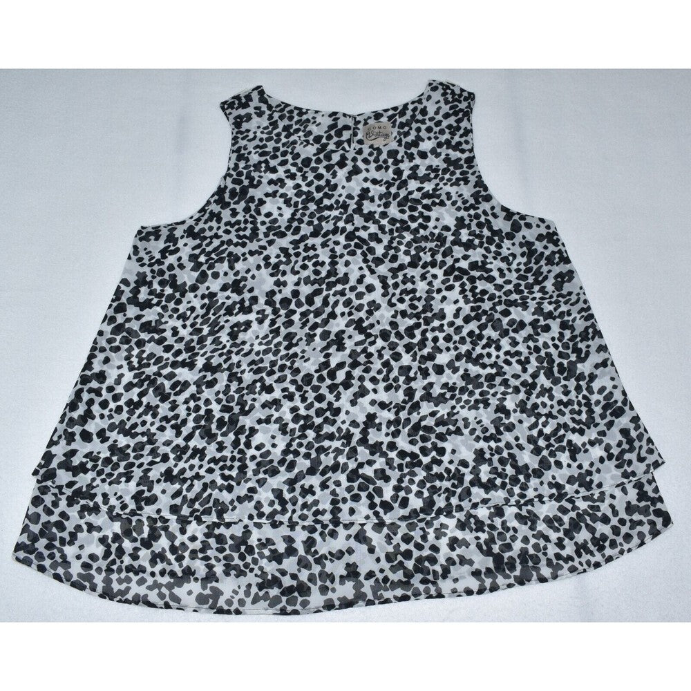 A sleeveless top with a black and white spotted animal print pattern, laid flat on a light gray background.