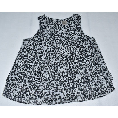 A sleeveless top with a black and white spotted animal print pattern, laid flat on a light gray background.