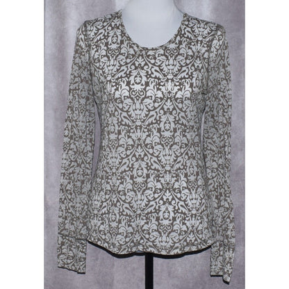 A long-sleeve scoop-neck blouse with an all-over damask pattern in brown and off-white, displayed on a mannequin torso against a textured gray backdrop.