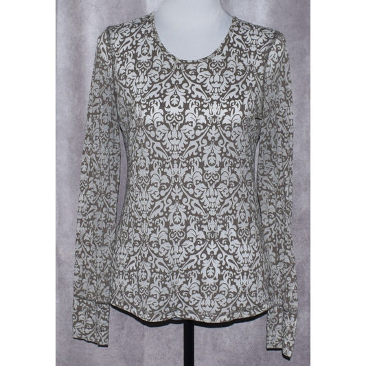 A long-sleeve scoop-neck blouse with an all-over damask pattern in brown and off-white, displayed on a mannequin torso against a textured gray backdrop.
