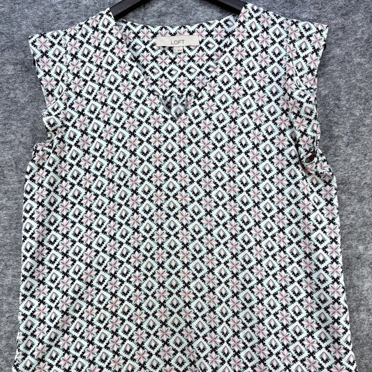 A sleeveless V-neck top with a geometric diamond pattern in black, white, and light pink, hanging on a black hanger against a gray textured background.