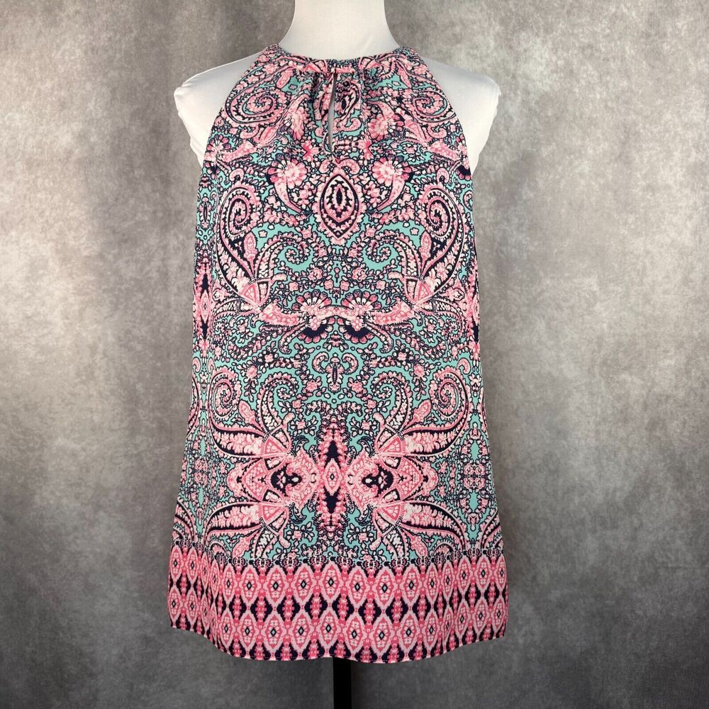 A sleeveless halter-neck top with a vibrant pink, teal, and black paisley pattern, displayed on a white mannequin torso against a textured gray background.