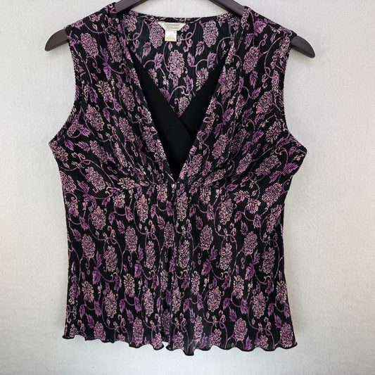 A sleeveless V-neck blouse with a black and purple floral pattern, hanging on a dark wooden hanger against a light gray textured wall.