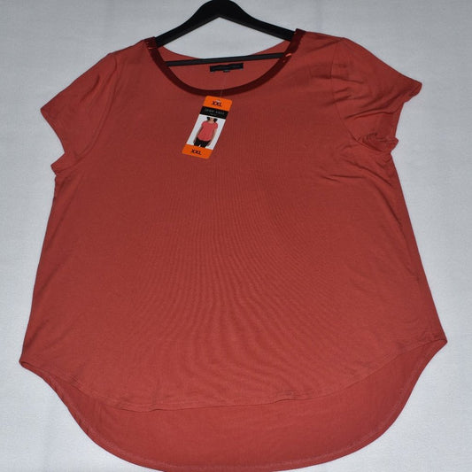 A rust-orange short-sleeve top with a curved hem, hanging on a black hanger against a light gray background. It features a contrasting dark red crew neck and has an orange retail tag attached.