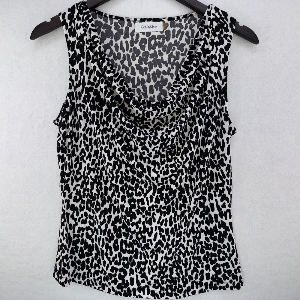 A Calvin Klein sleeveless top with a black and white leopard print pattern, hanging on a black hanger against a light gray textured background.