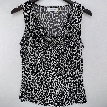 A Calvin Klein sleeveless top with a black and white leopard print pattern, hanging on a black hanger against a light gray textured background.