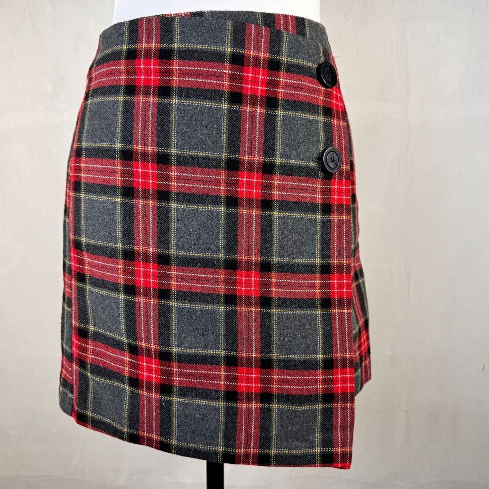 A plaid mini skirt in red, black, and gray with thin yellow stripes, displayed on a mannequin torso against a light gray fabric backdrop.