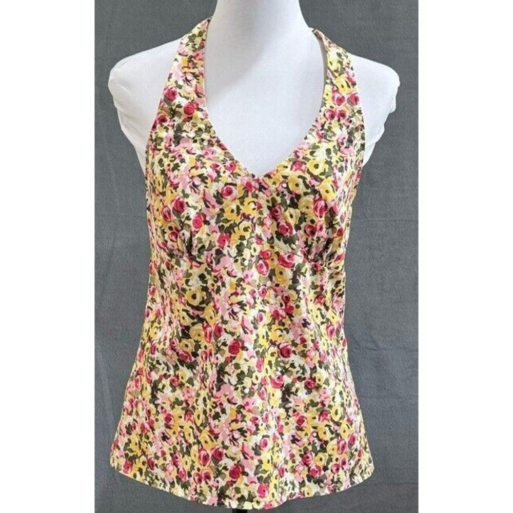 A sleeveless halter-style tank top with a dense multicolor floral print, displayed on a white mannequin torso against a dark gray background.