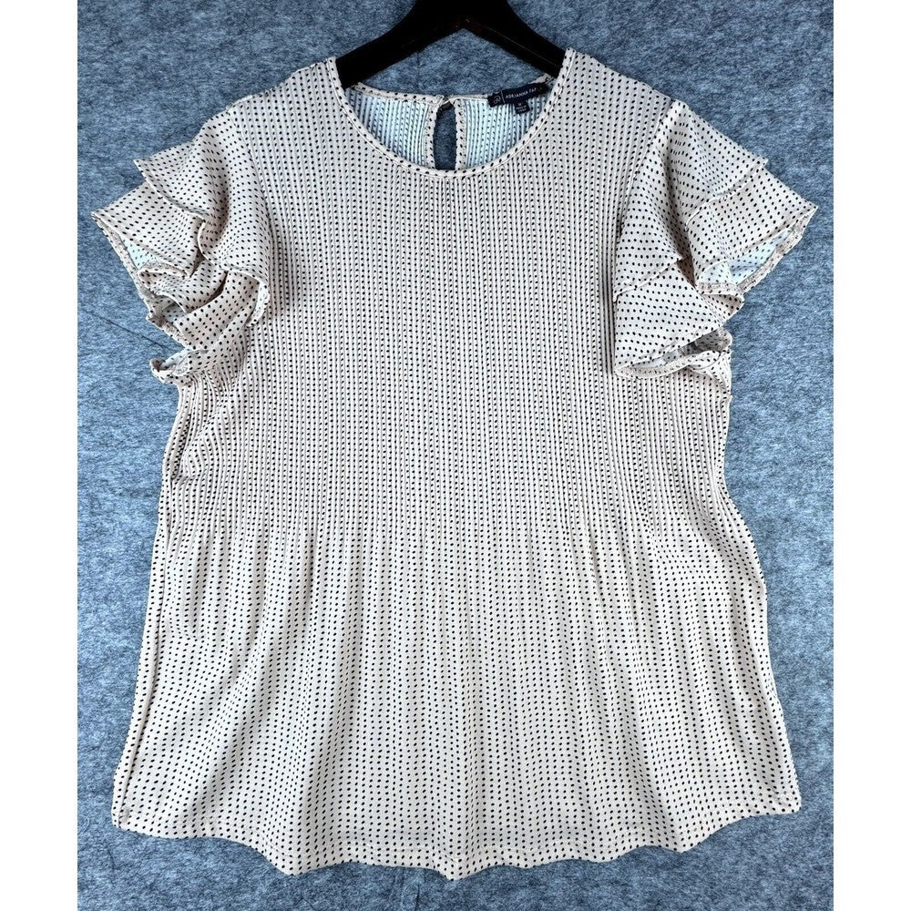 A short-sleeve blouse with flutter sleeves and a scalloped hem, featuring a small black and white geometric pattern, hanging on a black hanger against a textured gray background.