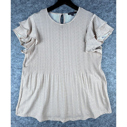 A short-sleeve blouse with flutter sleeves and a scalloped hem, featuring a small black and white geometric pattern, hanging on a black hanger against a textured gray background.