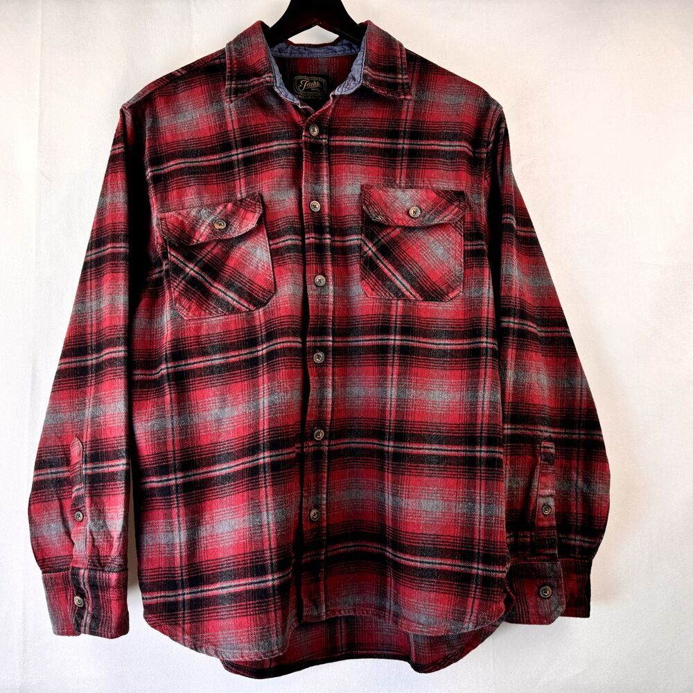 A red and black plaid long-sleeve button-up flannel shirt hanging on a black hanger against a white background.