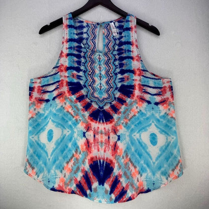 A sleeveless tank top with a vibrant blue, red, and white tie-dye pattern, hanging on a black hanger against a light gray textured wall.