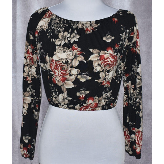 A long-sleeve crop top with a black base and a red, beige, and white floral rose pattern, displayed on a white mannequin torso against a gray textured background.
