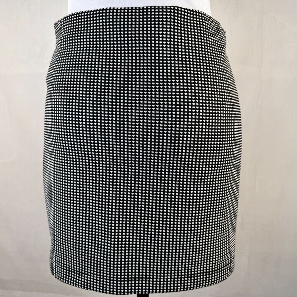 A black and white micro-check patterned mini skirt displayed on a white mannequin torso against a light beige background.