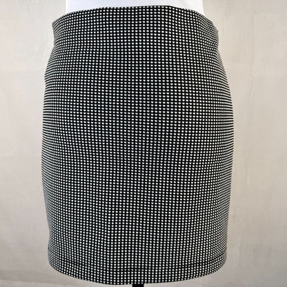 A black and white micro-check patterned mini skirt displayed on a white mannequin torso against a light beige background.