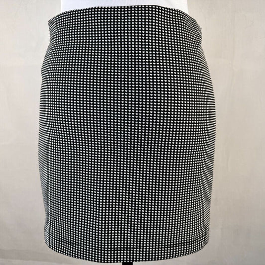 A black and white micro-check patterned mini skirt displayed on a white mannequin torso against a light beige background.