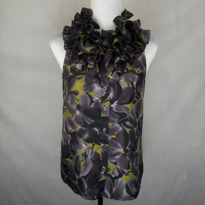 A sleeveless button-front blouse with a large ruffled collar, featuring a dark gray and black floral pattern with olive green accents, displayed on a white mannequin torso against a light gray backdrop.