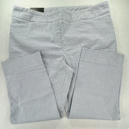 A pair of folded pants with a fine vertical stripe pattern in navy blue and white, laid flat on a light gray background.