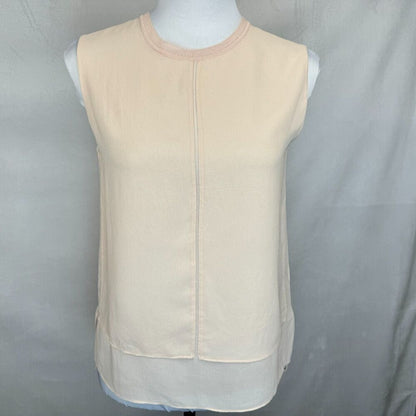 A sleeveless cream-colored top with a round neckline and a central seam, displayed on a white mannequin torso against a gray fabric backdrop.