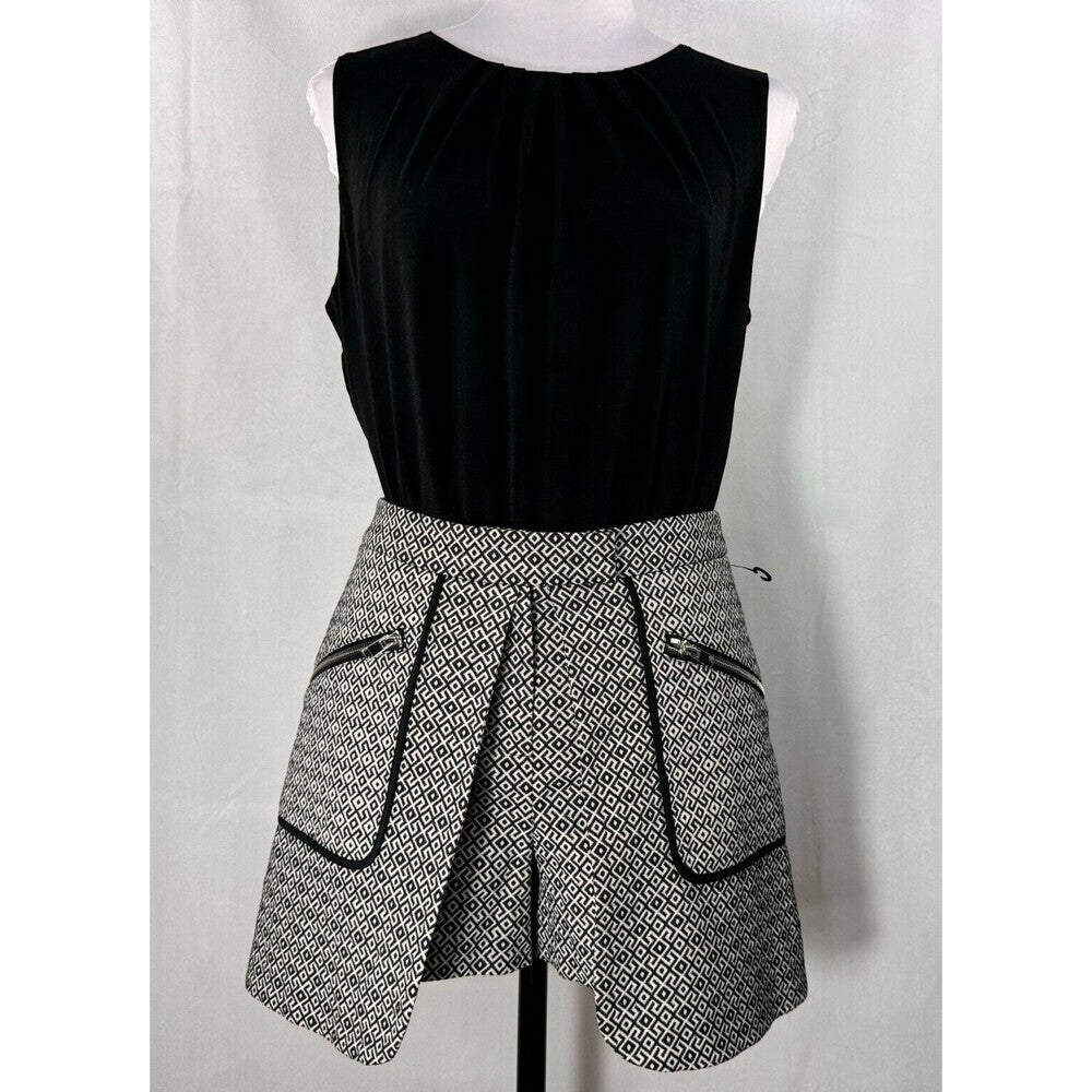 A sleeveless black top paired with a black and white patterned asymmetrical skirt featuring zippered pockets, displayed on a mannequin against a white backdrop.