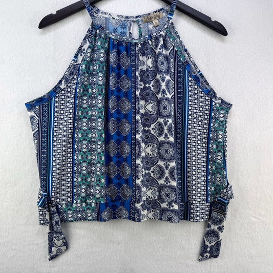 A sleeveless halter-style top with a multicolor bohemian print in blue, navy, green, and white, hanging on a black hanger against a textured white wall.