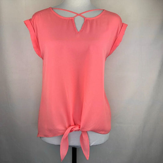 A coral pink short-sleeve blouse with a keyhole back and front tie detail, displayed on a white mannequin torso against a light gray fabric backdrop.