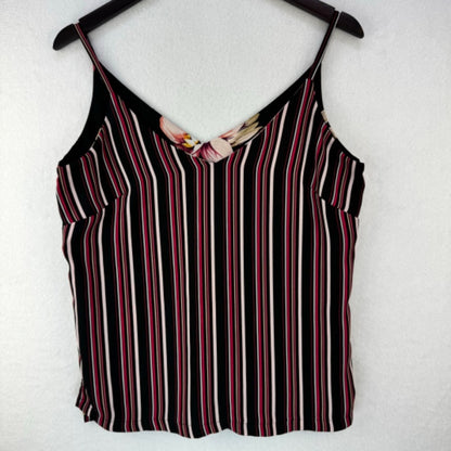 A sleeveless striped camisole top hanging on a black hanger against a white textured wall. The top features vertical stripes in black, white, and red, with a small floral accent at the V-neckline.